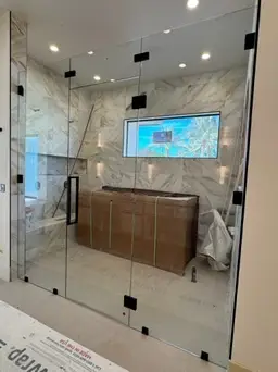 Modern Ahwatukee bathroom remodel with large frameless glass shower, marble tile walls, and black hardware by Drill Renovations.